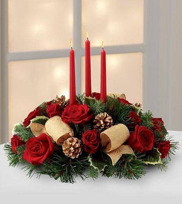 Celebration of the Season - red roses , red spray roses , holiday greens , variegated holly , red candles , gold pinecones , gold metallic brocade ribbon , centrepiece