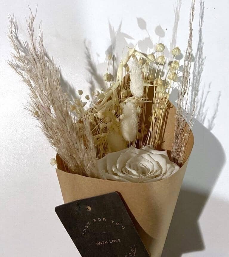 Exquisite design with tropical dried flowers and a preserved white rose.